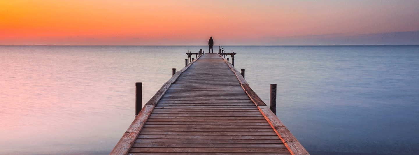 Man on the pier looking out towards the sunset