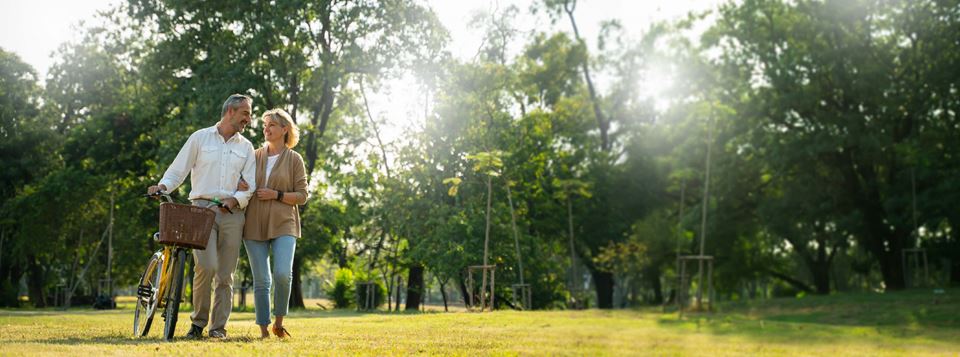 Couple walking in a grassy field with a bike