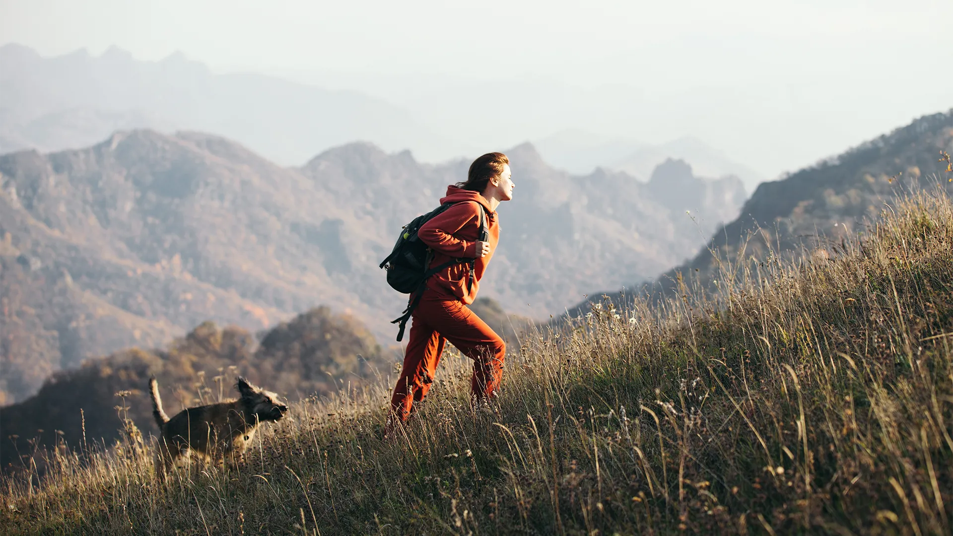 Female hiking up a hill with her dog.