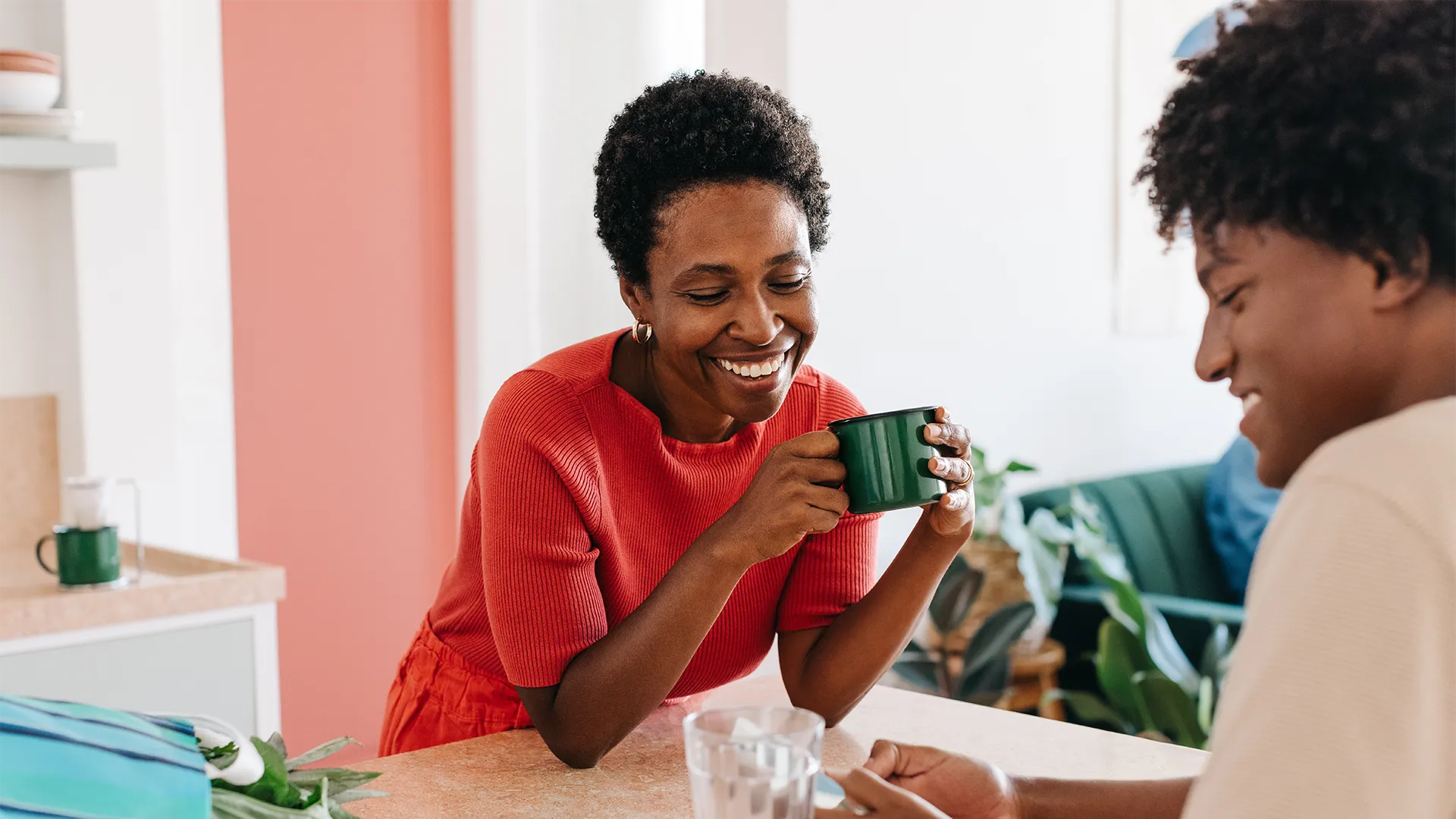 A woman holding a coffee mug while talking to another person.