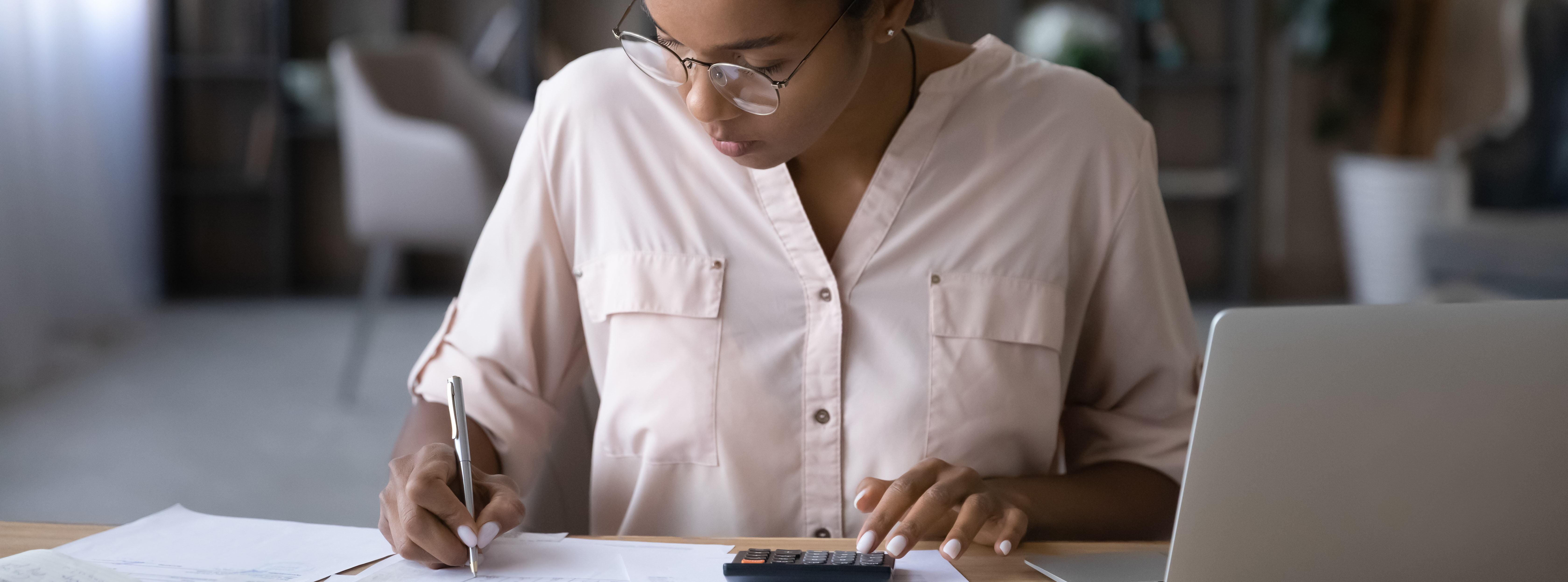Young multiracial woman using calculator