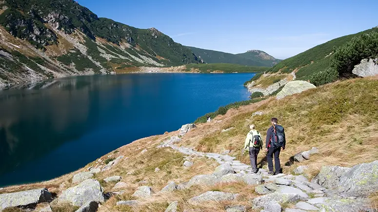 A couple walking hand in hand by a lake.