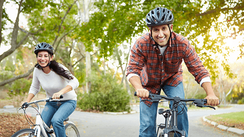 Man and woman riding bikes through a park