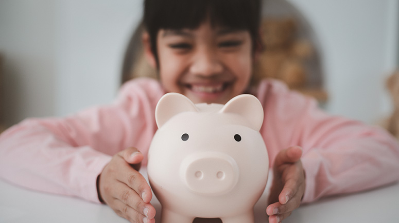 Girl holding piggy bank up to the camera