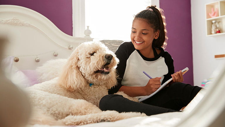 Dog sitting with girl on bed