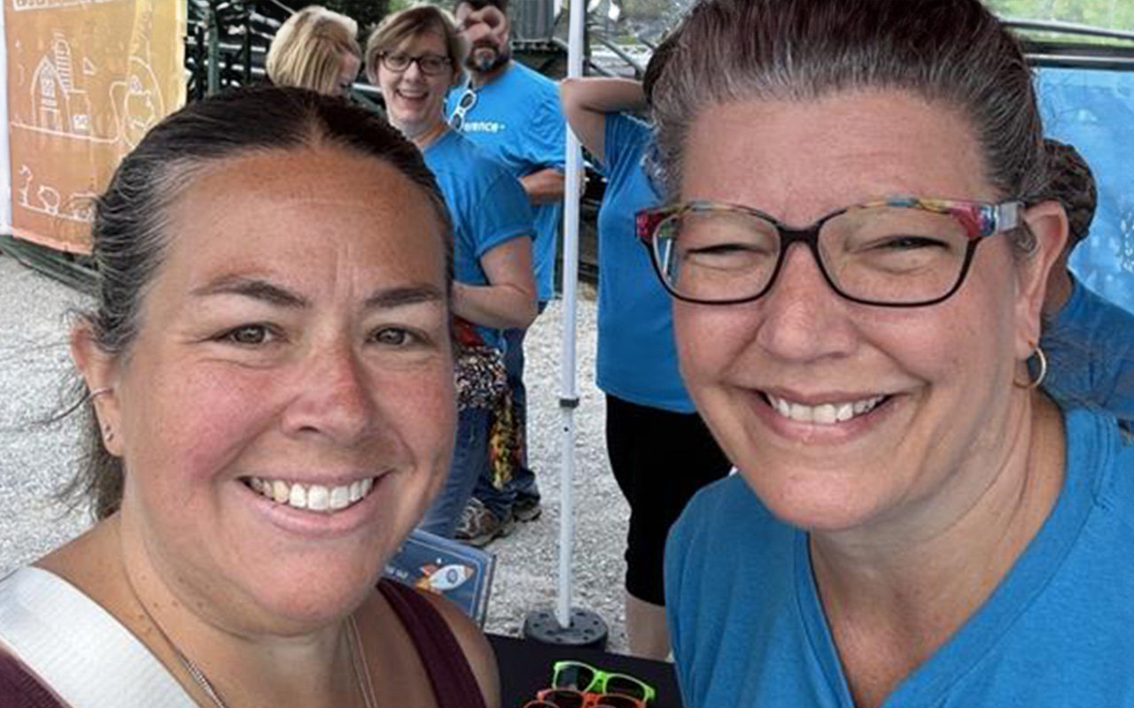 Everence employees, Dawn Ergle and Andrea Kruze, smile at the Everence Entertainment center at the Elkhart County 4-H Fair.