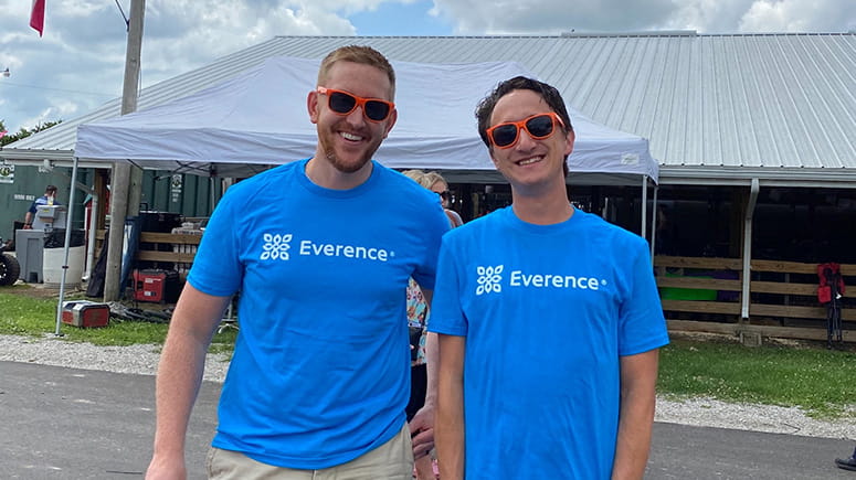 Two Everence employees pose wearing their blue Everence shirts and Everence sunglasses.