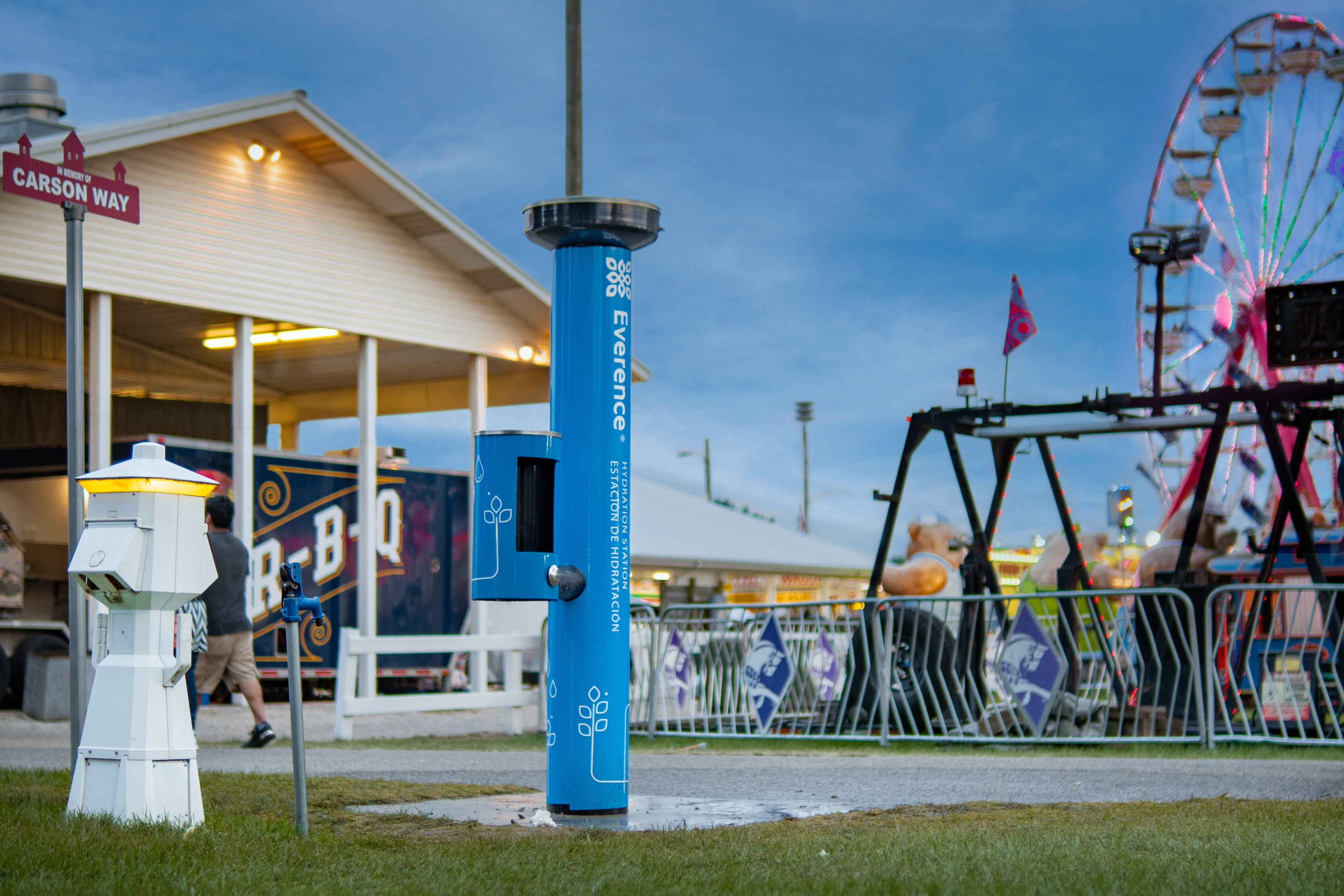 Everence hydration station stands center frame with the Elkhart County 4H fair food and rides in the background.