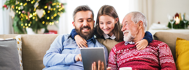 Father, daughter, and grandfather look at an electronic device