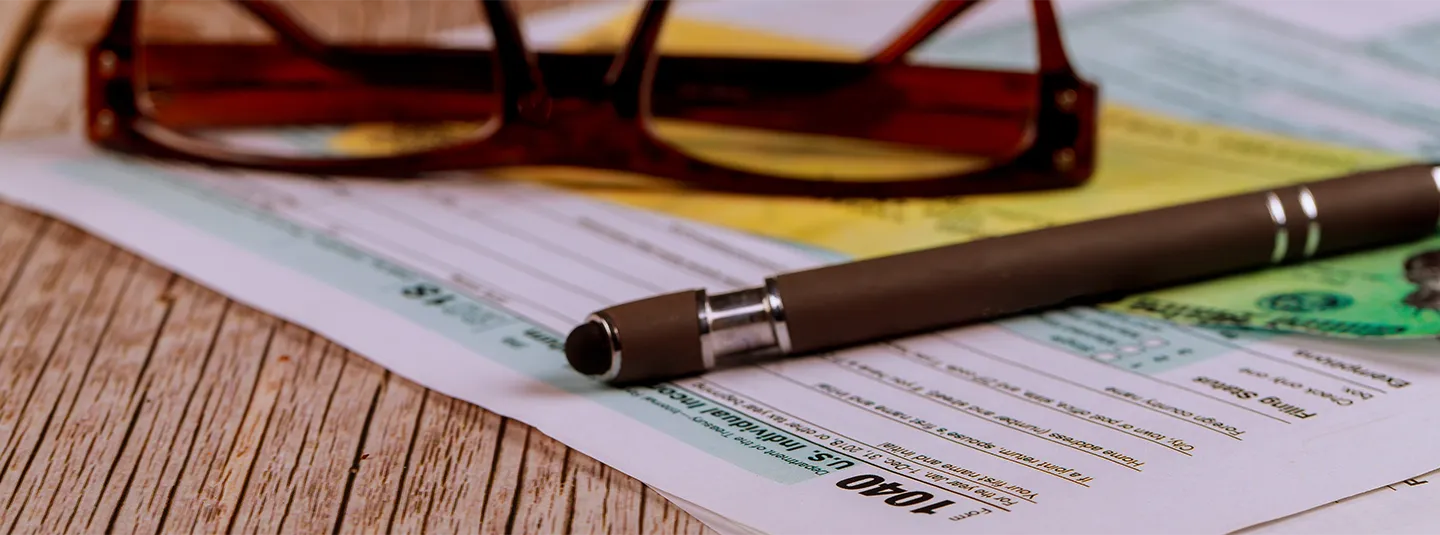 A 1050 tax form sitting on a table with a pair of glasses and pen sitting on top of it. 