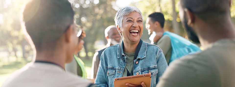 A smiling woman signs up volunteers for community clean up