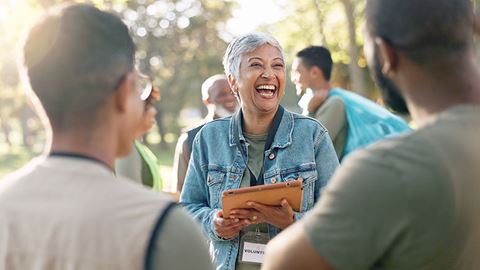 A smiling woman signs up volunteers for community clean up