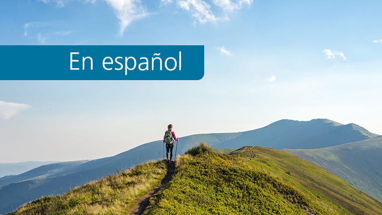 Young woman hiking in the mountains. This resource is in Spanish