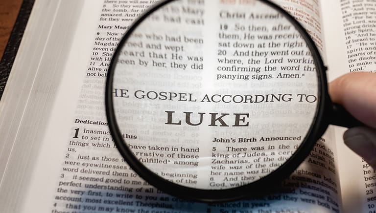 Magnifying glass over the Gospel of Luke in the Bible