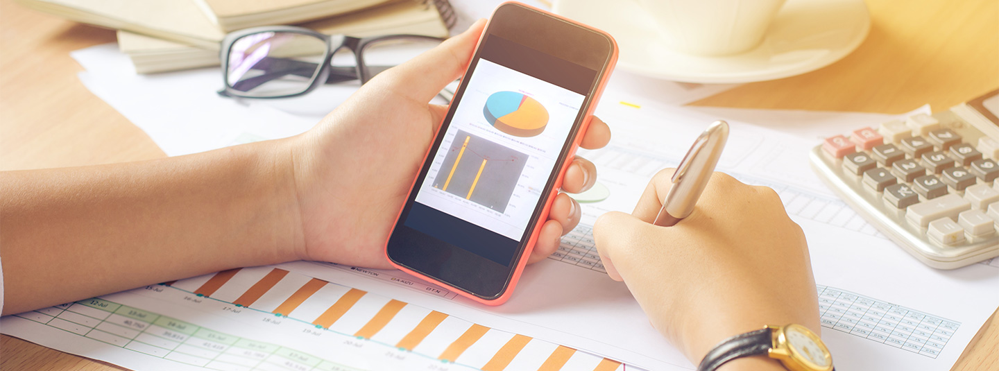 Woman with graphs on paper and mobile phone