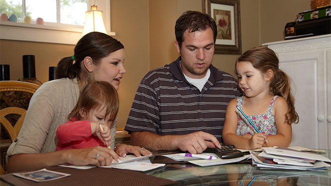 Carrie and Dan Kane look over finances while daughters Adella and Lilly color.